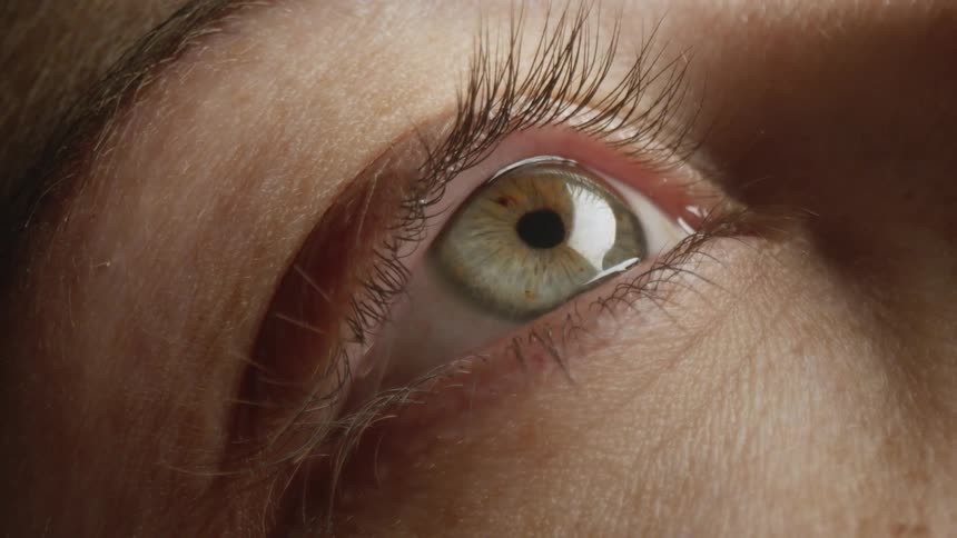 A woman opens her eyes after light moves across her face