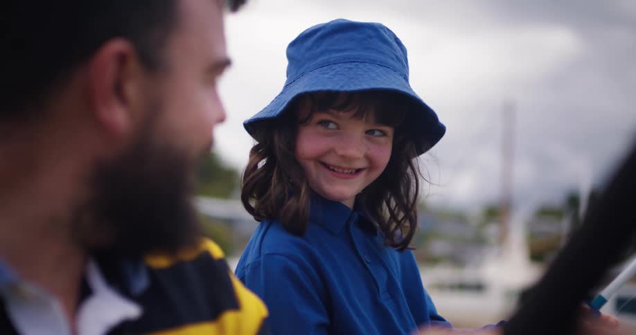 Father with beard and daughter with blue hat and shirt fish on the coast on a cloudy day