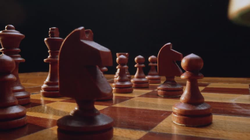 A persons hand moves a piece on the chess board