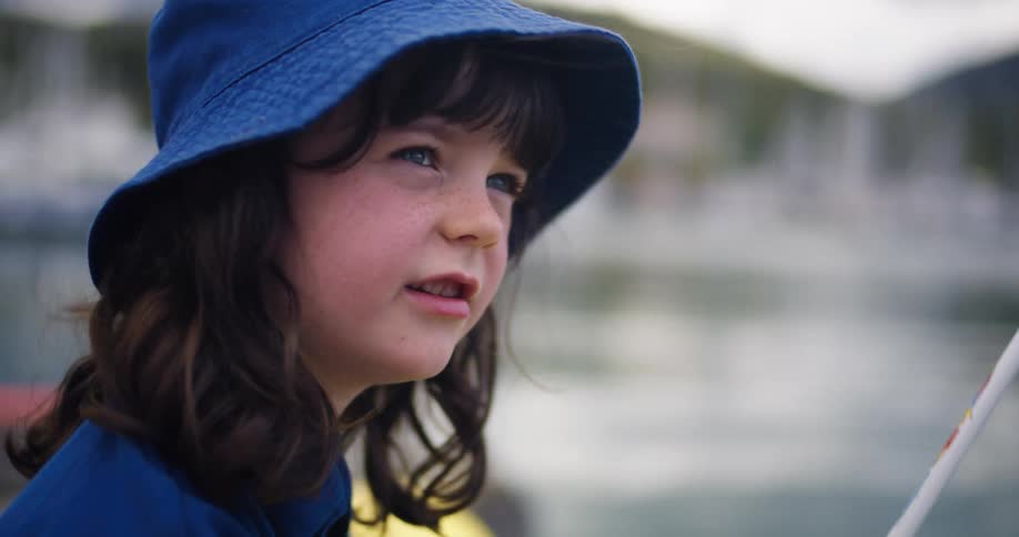 A kid is on a boat and is fishing on a lake in the day time
