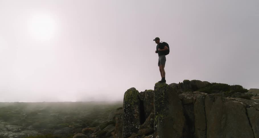A man is hiking through a mountainous landscape at dusk
