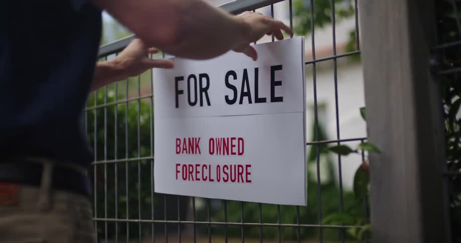 Someone is putting a sign on a fence to sell there house