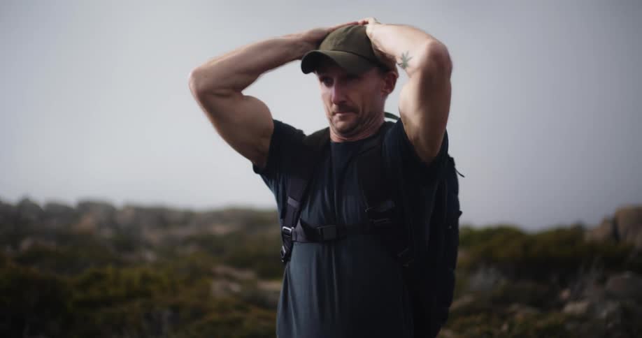 A man out hiking puts on his hat and starts to run