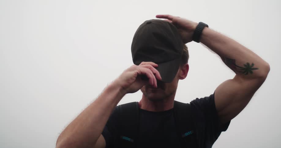 A man puts his baseball cap on outdoors