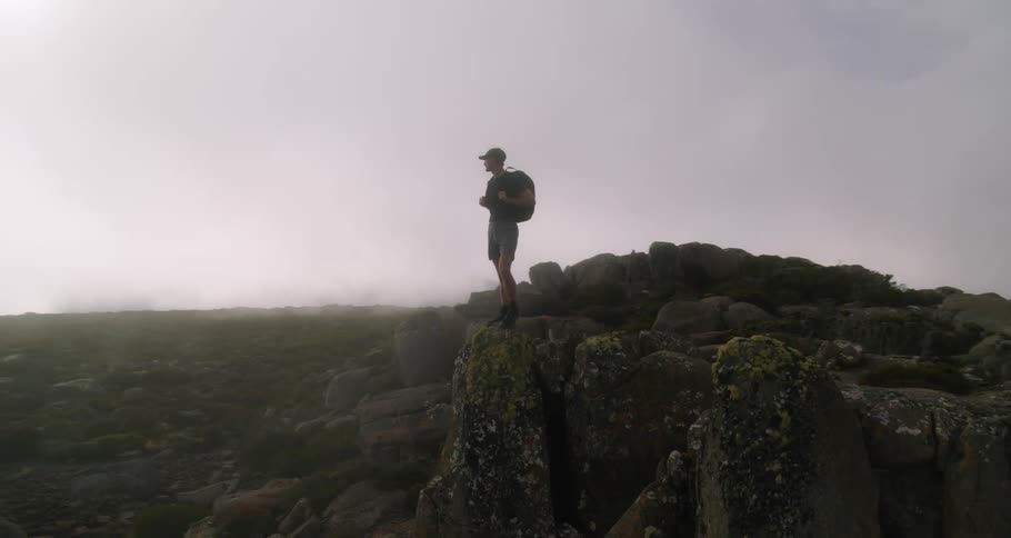 A man is standing on a cliff and looking at the view outdoors