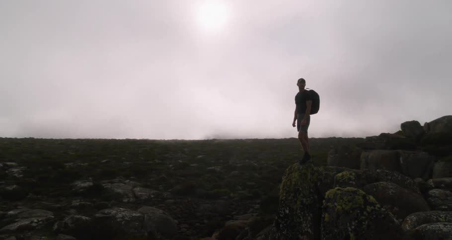 The view is of a man standing on a cliff in the middle of the day