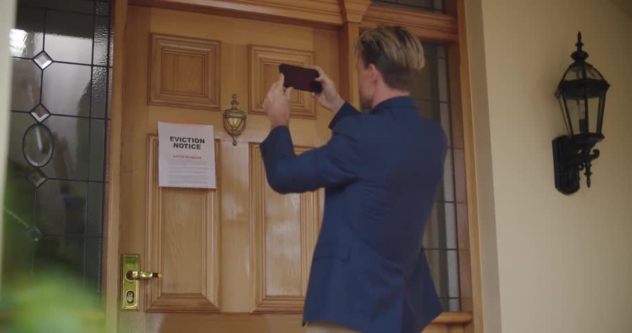 A man is putting a letter on someones door