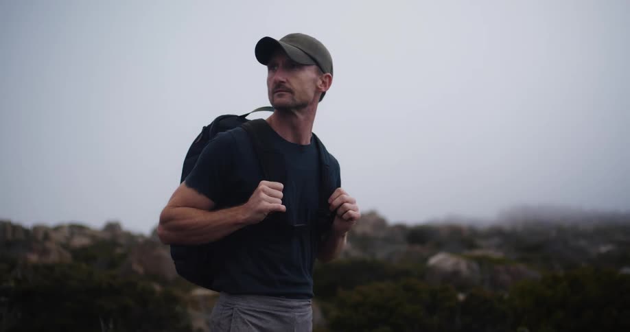 A man stopping to catch a breath while hiking with a backpack