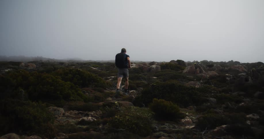 A man is jogging through a rocky terrain
