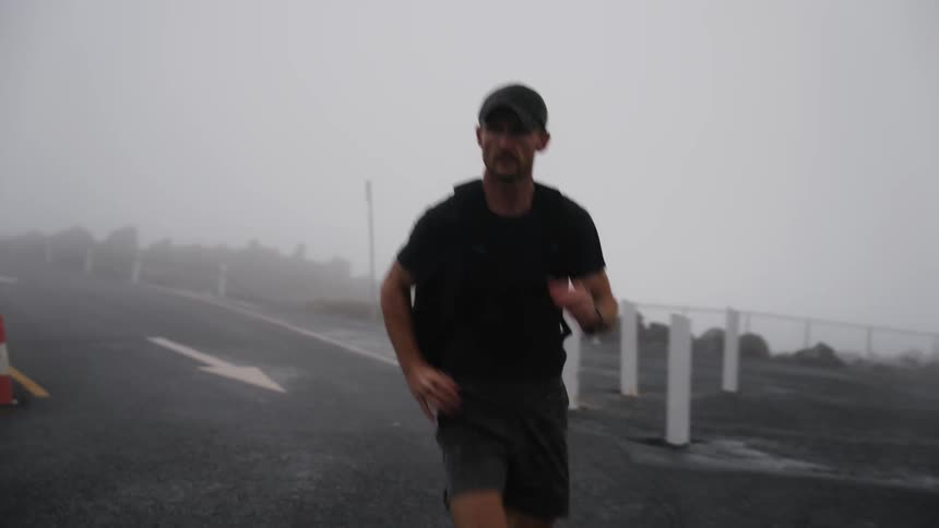 A man runs along a foggy road during the day