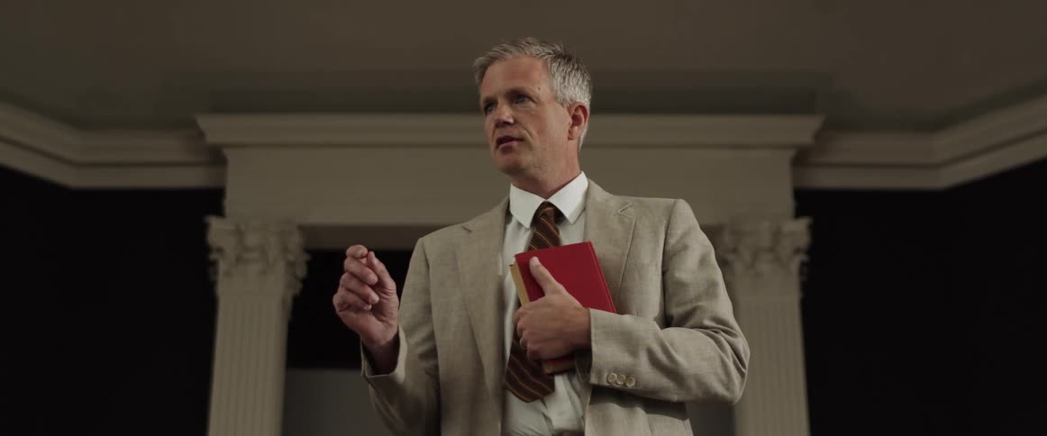Man holding book stands while giving talk