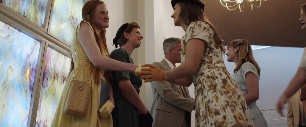 Church congregation shakes hand with preacher and his family near stained glass window