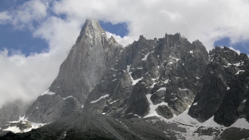 A mountains is surrounded with clouds and snow