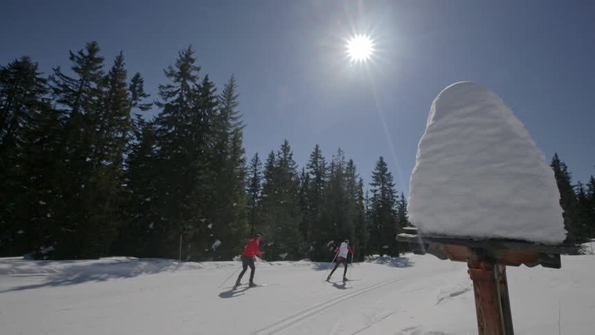 People ski up a slope on a sunny day