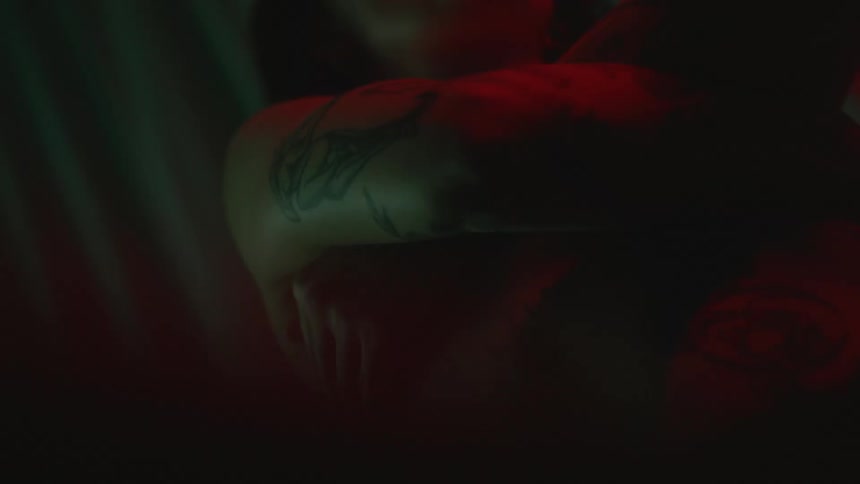 A woman with tattoos moves in the dark