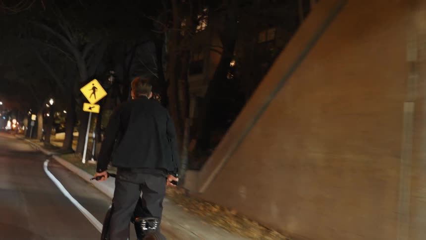 A young man is riding is bike down the street at night time