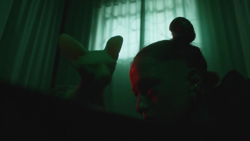 Woman leans near cat sculpture in dimly lit room