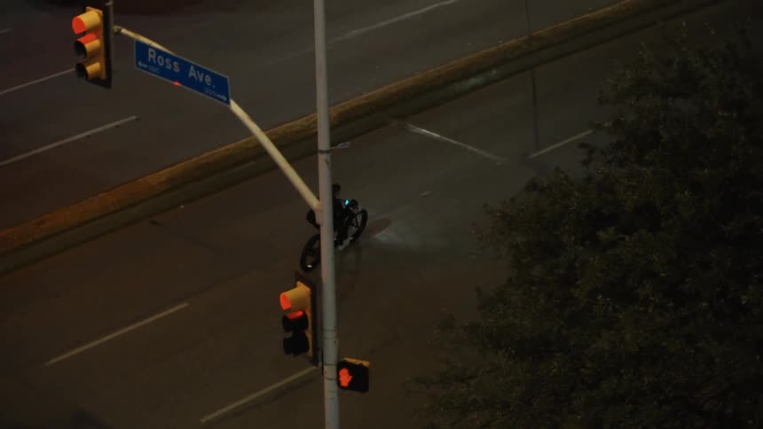 An aerial view of a man riding a motorbike down a city street