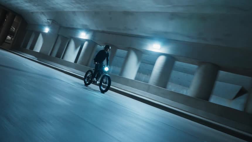 A man riding a motorbike down the road with a head light on