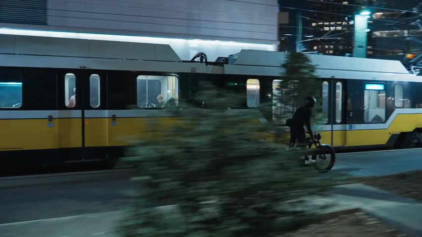 A young man is riding his bike downtown in the middle of the night