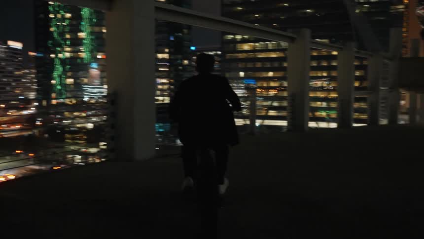A young man is riding his bike downtown at night time
