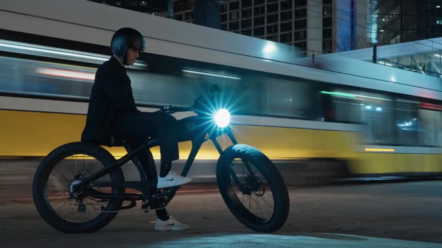 Slow motion of a person sitting on a bike in a city is displayed
