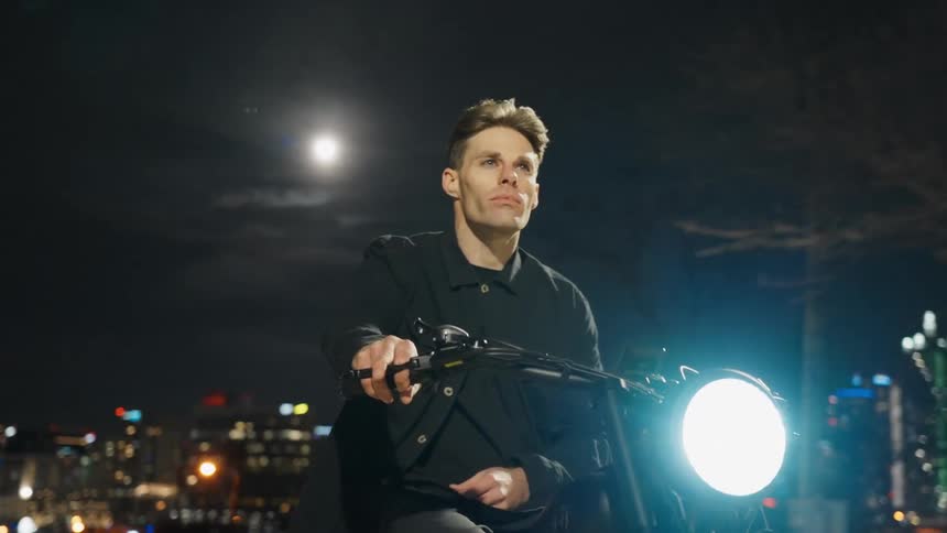 A young man is riding his bike downtown in the middle of the night