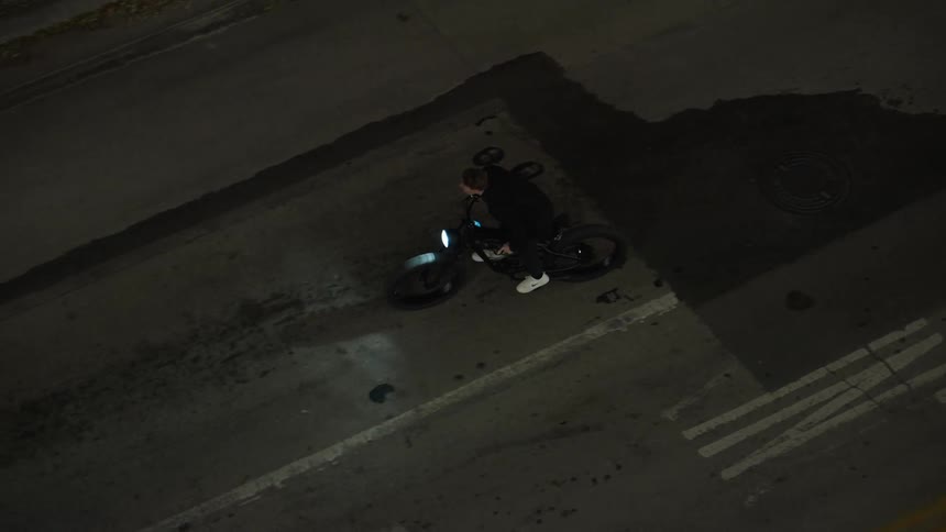 A young man is riding his bike down downtown at night time