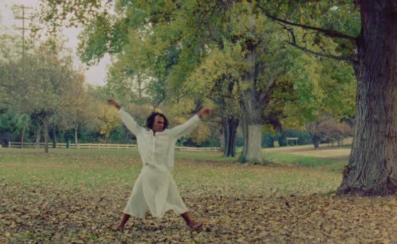 A young man is dancing outside around the nature area