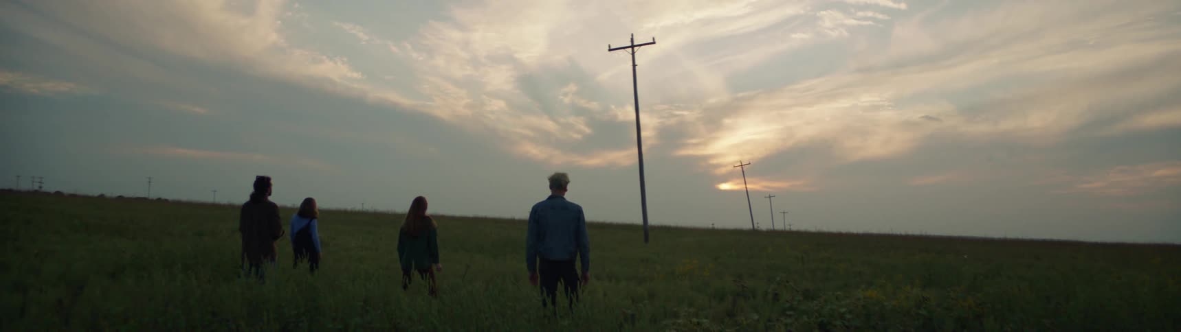 A group of people stand in a field with utility poles
