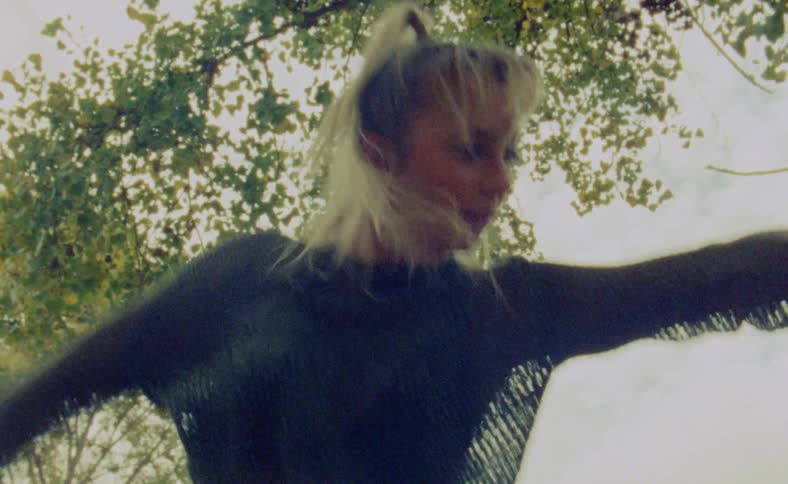 A woman is dancing outdoors during the summer time