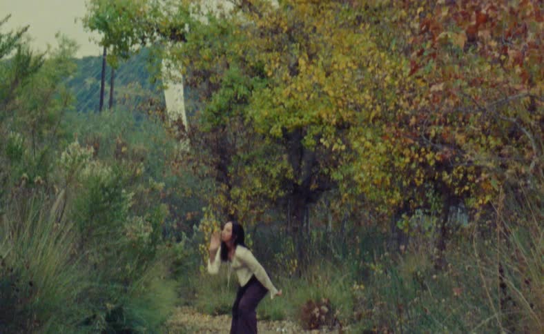 Woman dances on path near trees with fall foliage