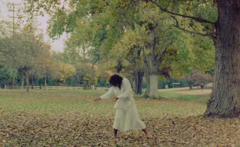 A woman is dancing outdoors during the autumn season