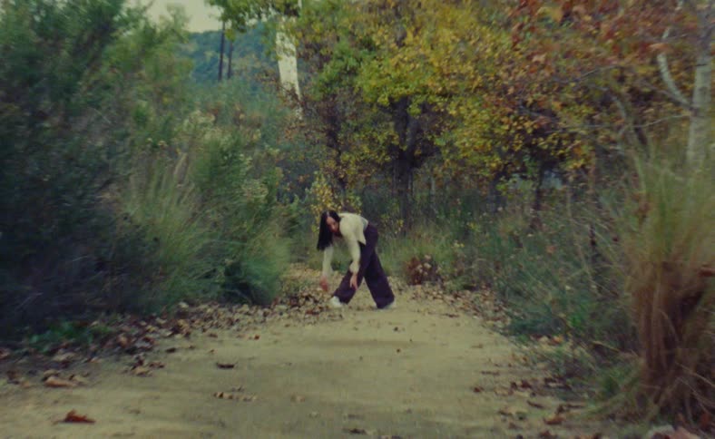Woman dances on path near tree with fall foliage