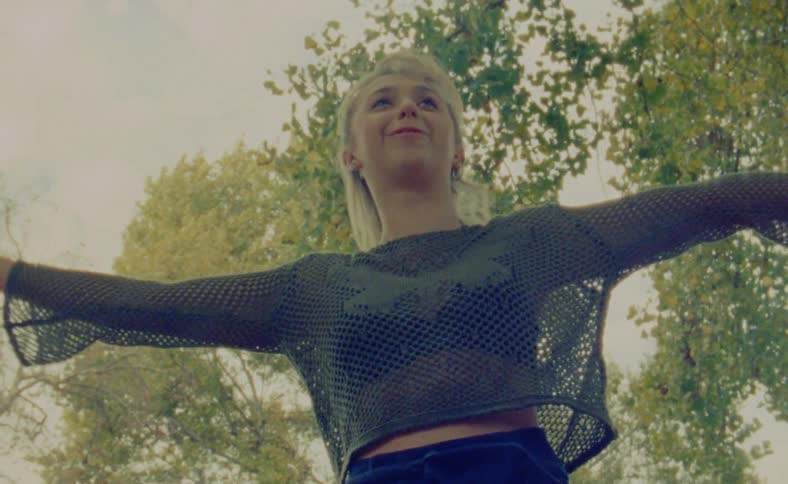 A girl is standing outside on a windy day and swaying her arms back and forth