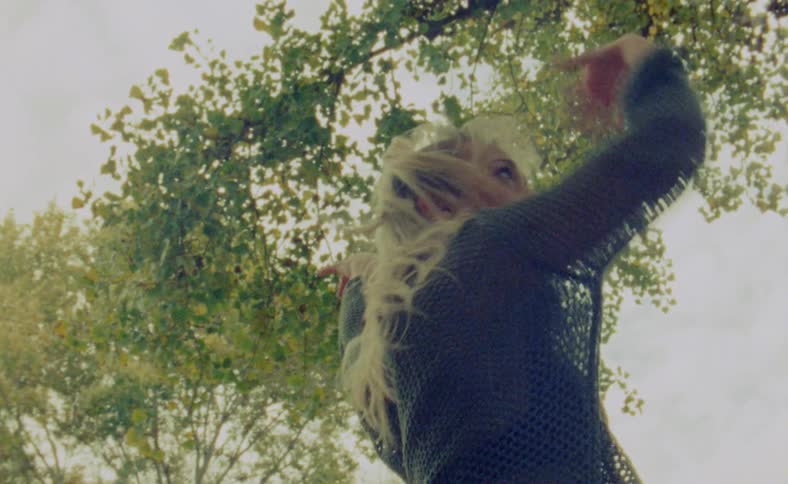 A young woman is dancing outdoors in the middle of the day time