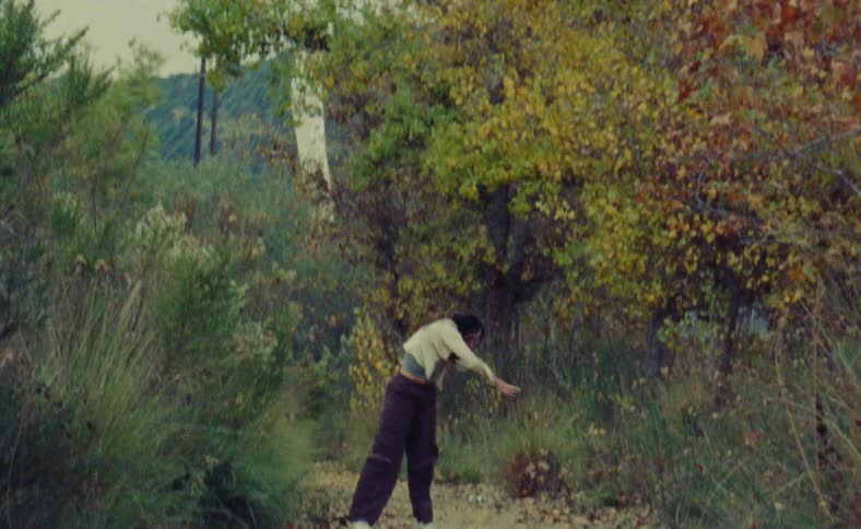 A woman dancing and moving in nature on a path