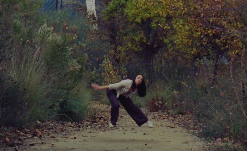A woman is dancing in a forest during the autumn season
