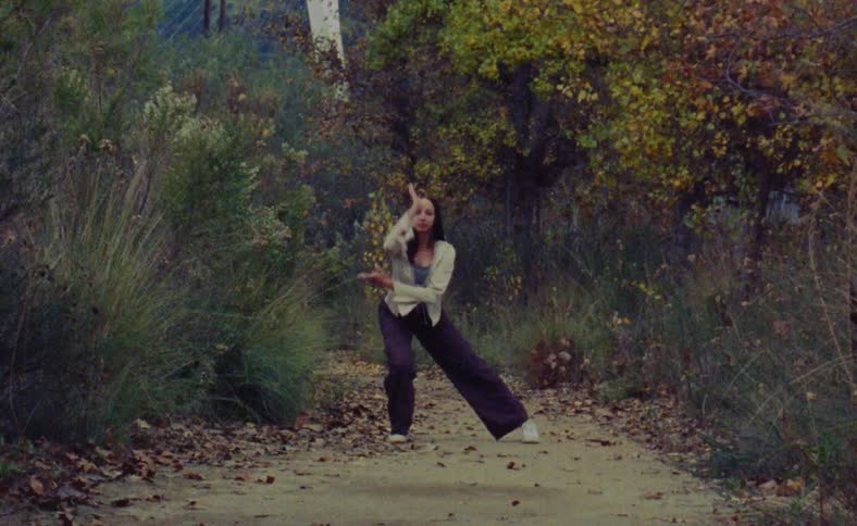 The view is of a woman that is dancing outside in the day time