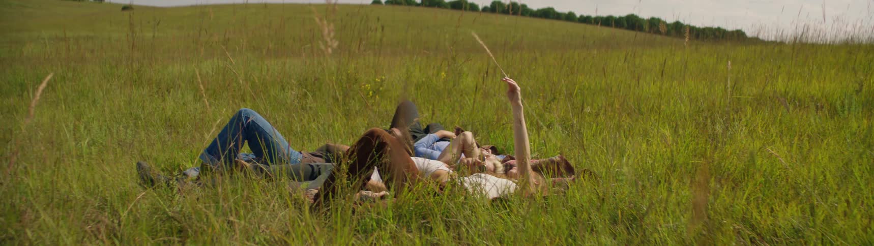 A group of friends are laying in the grass together