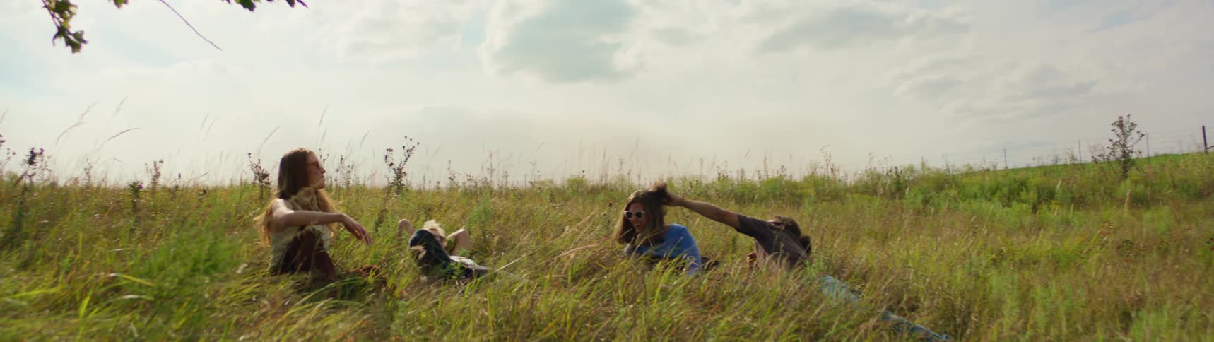 A group of friends are sitting in a field of grass together