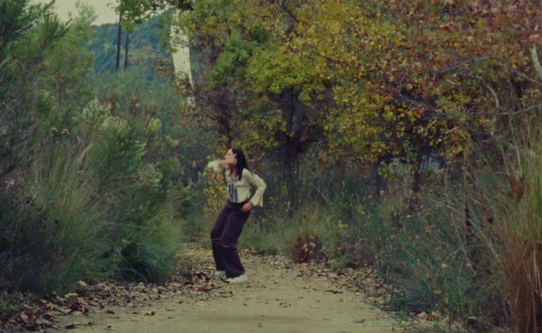A woman is dancing outdoors during the autumn season