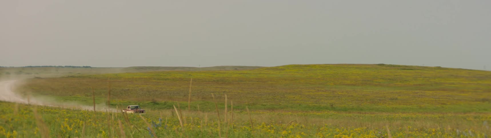 A truck is driving through a rural area at dusk