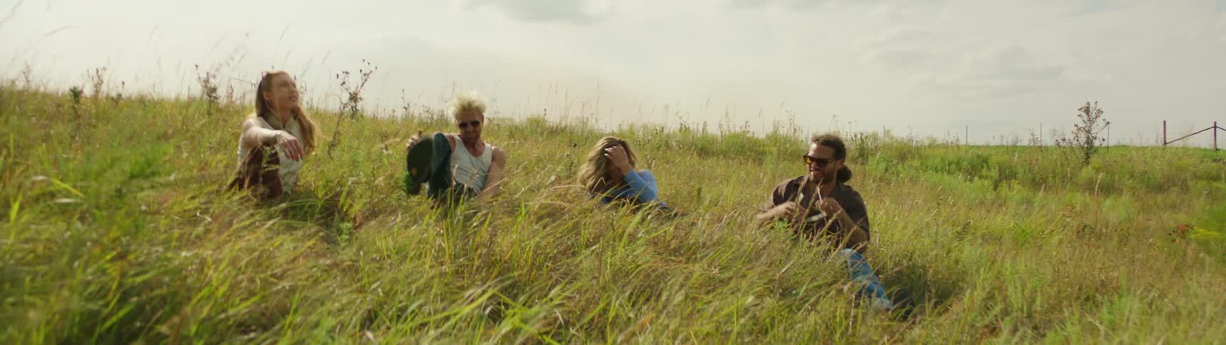 Four friends are sitting outdoors in a field together