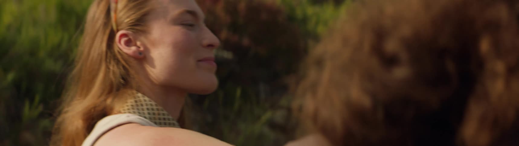 A woman is smiling and sitting outdoors next to a friend