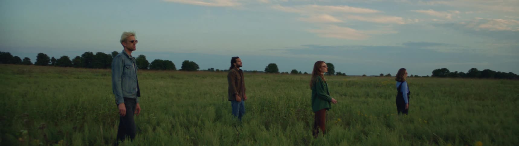 A group of four people are standing in a field together