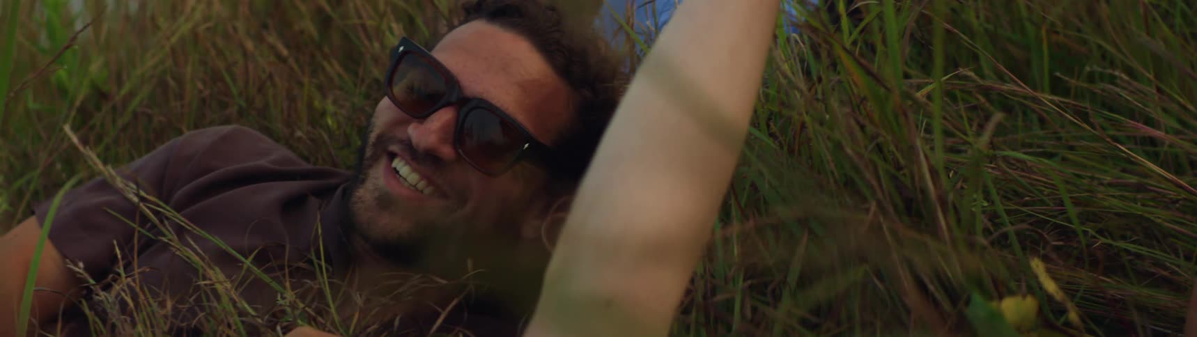 Friends are laying in a field of grass outside in the middle of the day time
