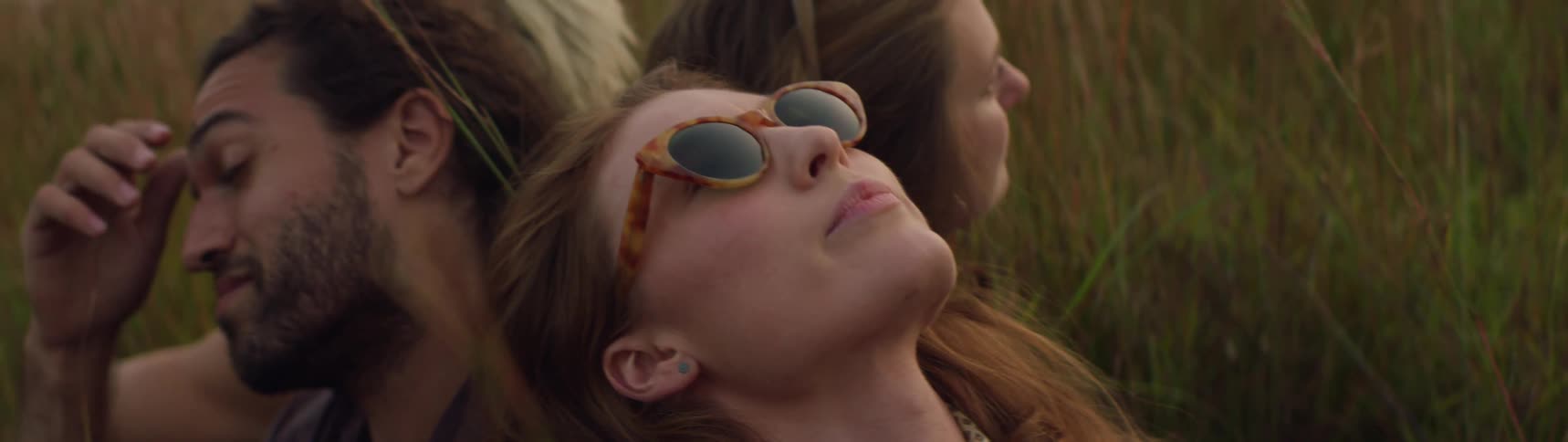 Three friends are sitting in a field of grass together
