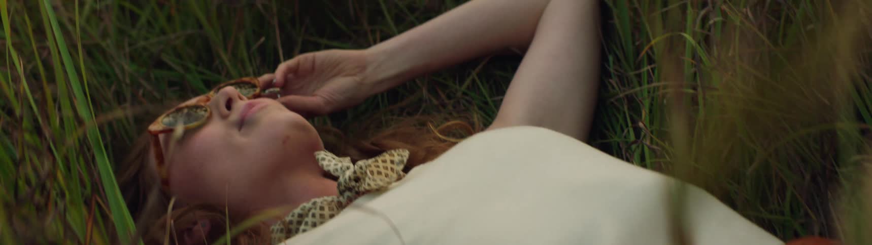 A woman is resting and laying in a grass field