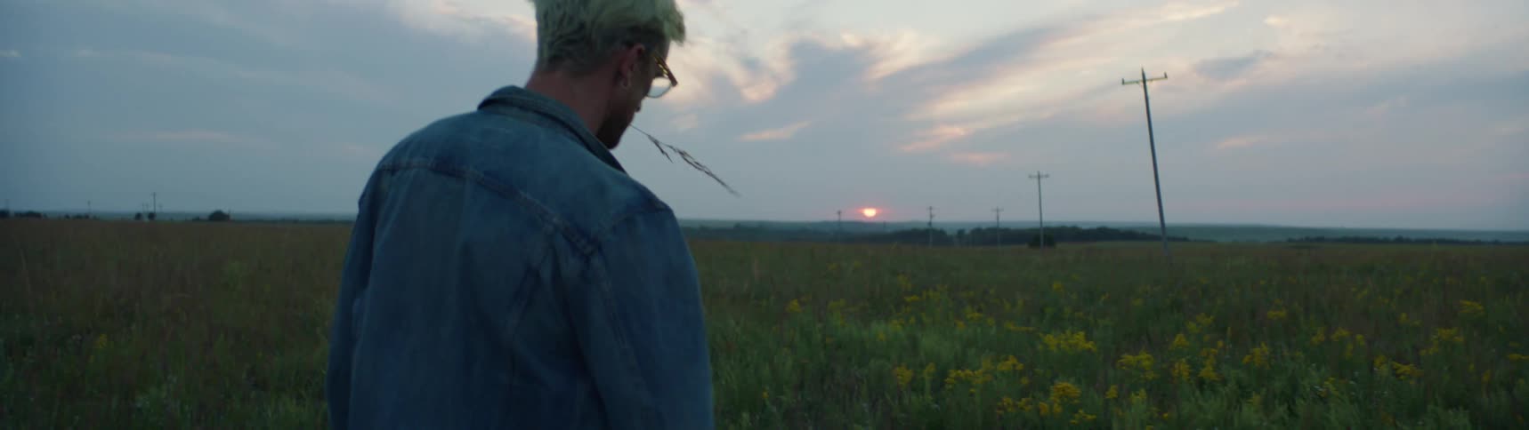 A man is standing outdoors in a grassland area